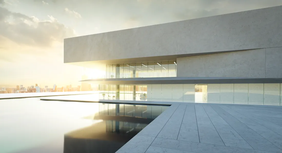 Edifício de concreto claro com fachada envidraçada refletida num espelho d'água ao amanhecer.